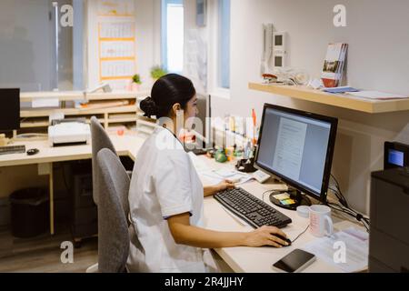 Side view of female healthcare worker using desktop PC at hospital Stock Photo