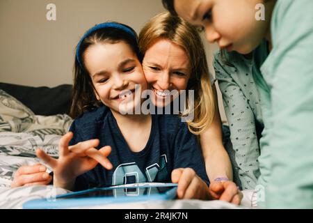 Happy woman with sons using digital tablet at home Stock Photo