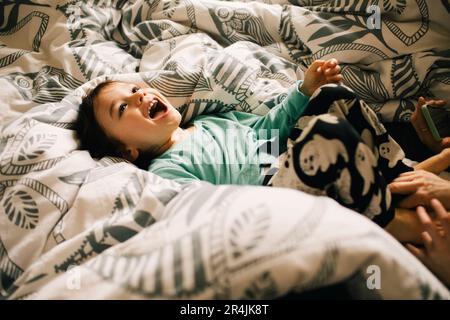High angle view of happy boy lying on bed at home Stock Photo