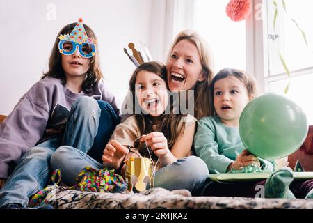 Cheerful mother with children enjoying birthday party at home Stock Photo