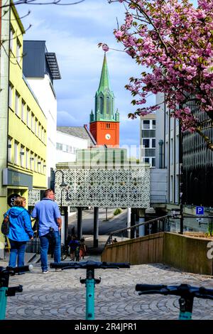 Stavanger, Rogaland, Norway, May 19 2023, Man And Woman, Couple Walking Old Town Stavanger Shopping Area With historic Church Steeple In The Backgroun Stock Photo
