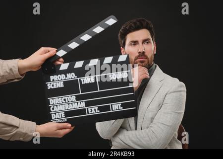 Actor performing while second assistant camera holding clapperboard on black background Stock Photo