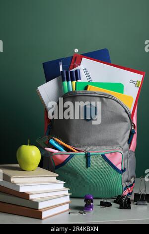 Backpack with different school stationery on white table near chalkboard Stock Photo