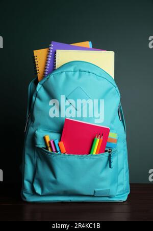 Backpack with different school stationery on white table near chalkboard Stock Photo