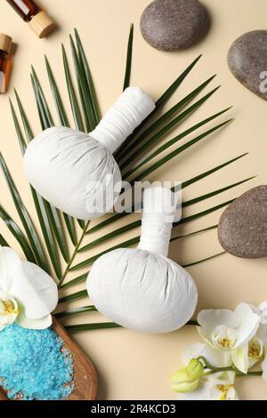 Flat lay composition with herbal massage bags and other spa products on beige background Stock Photo