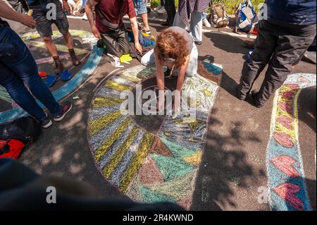 A young girl draws colourful graffiti and Extinction Rebellion logo on tarmac, during the demonstration. Police used water cannon against Extinction Rebellion demonstrators and their supporters, in The Hague. This was the seventh time this section of the A12 on the Utrechtsebaan has seen similar protests and was banned by the municipally. Police used water cannon on low pressure in an attempt to disperse the demonstrations within minutes of them gathering. The protesters came ready with, umbrellas, protective clothing and, taking advantage of the warm spell; a few girls wore bikinis, and on mo Stock Photo