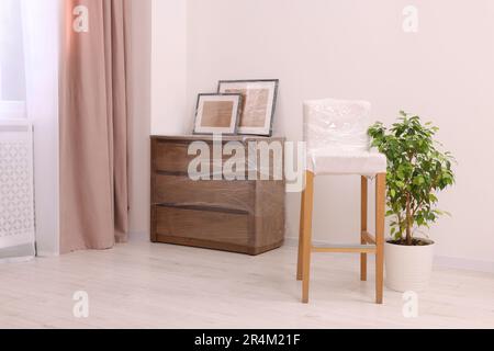 Picture frames, chair and chest of drawers wrapped in stretch film indoors Stock Photo