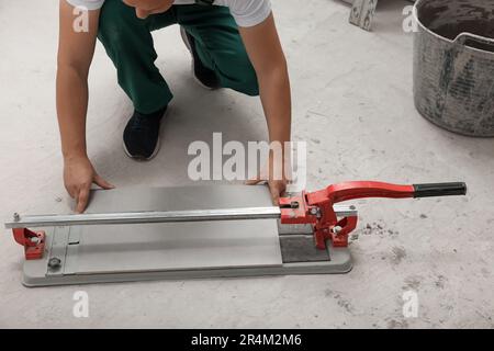 Worker using manual tile cutter on floor, closeup Stock Photo