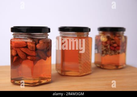 Jars with different nuts and honey on wooden table against white background Stock Photo