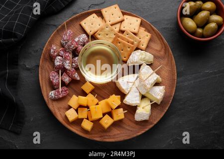 Toothpick appetizers. Pieces of cheese, sausage and honey on black table, flat lay Stock Photo