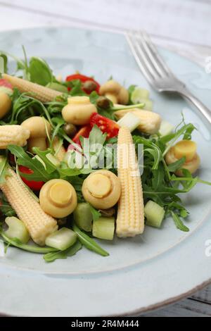 Tasty baby corn with vegetables, arugula and mushrooms on white wooden table, closeup Stock Photo