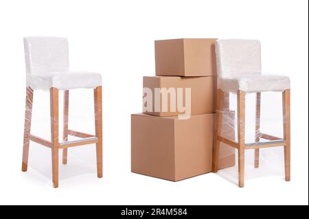 Chairs wrapped with stretch film and cardboard boxes on white background Stock Photo