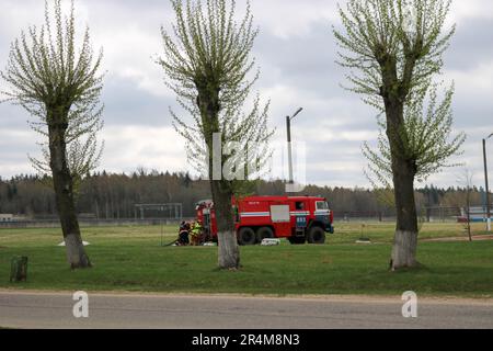 A large red fire rescue vehicle, a fire extinguishing truck, rides on a chemical, oil refinery in the background of trees. Stock Photo