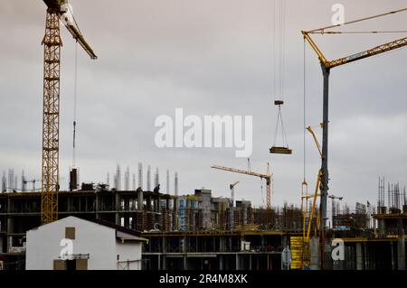 Working male builders are working on the roof of a large monolithic frame house, building, and new building under construction. Construction of the bu Stock Photo