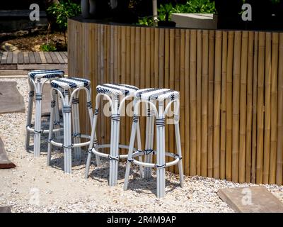 Empty four rattan bar stools, black and white patterns preparing for customer in front of the bamboo bar on the tropical beach. Tall round seat outdoo Stock Photo
