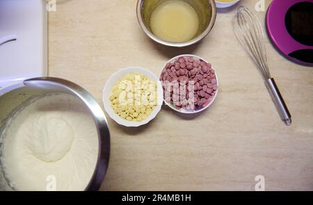 Top view marble kitchen worktop with ingredients for making a mousse cake. Whipped cream and chocolate chips in bowls Stock Photo