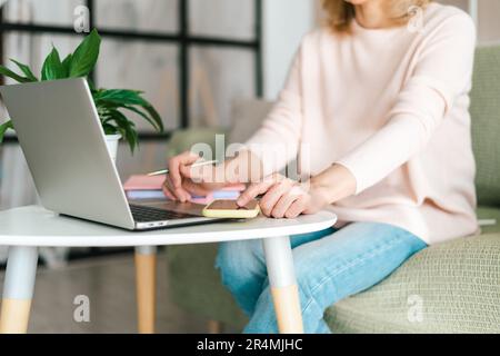 Cute adult senior mature woman in glasses checking text messages in her smartphone cell phone gadget, while doing online banking investment trading in Stock Photo