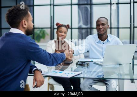 Overjoyed multiethnic businessmen shake hands greeting getting acquainted in office Stock Photo