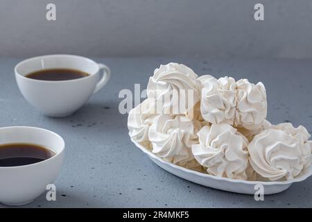 Homemade zephyr or marshmallows with a cup of coffee on a gray concrete background . side view, close-up, selective focus. Stock Photo