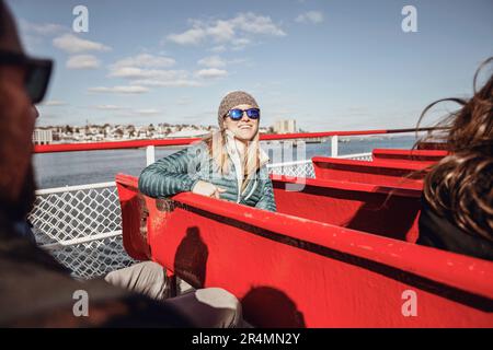 A young woman wearing glasses smiles while riding a ferry in Maine. Stock Photo