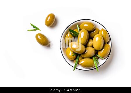 Green olives with rosemary leaves in white bowl, isolated on white background, top view. Stock Photo