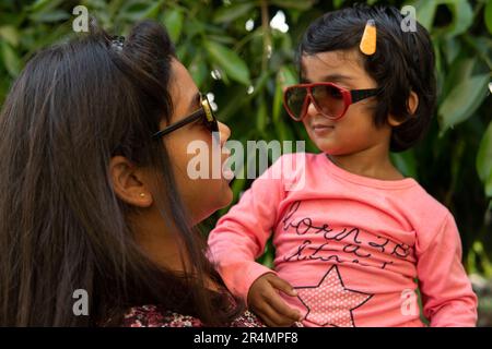 Sisters wearing sunglasses and interacting and making fun at outdoors Stock Photo