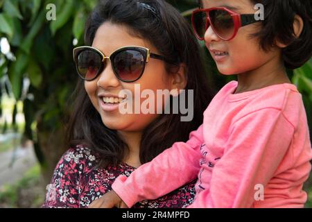 Sisters wearing sunglasses and interacting and making fun at outdoors Stock Photo