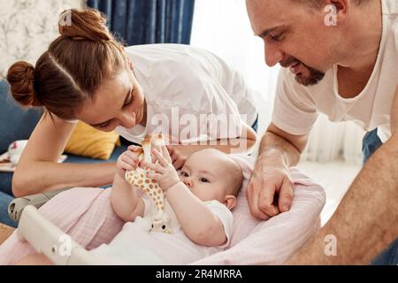 Happy smiling mom and dad leaned over their baby lying in the cradle ...