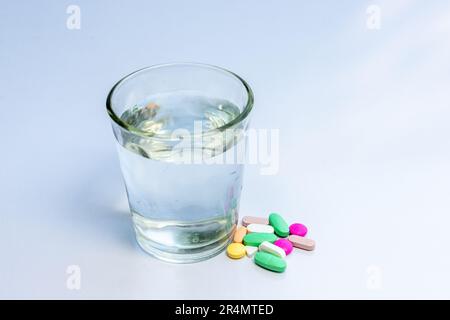 Various medical pills and tablets with a glass full of water Stock Photo