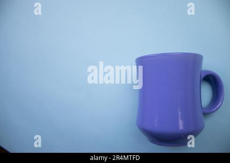 Blue mug, photographed from above, placed on the edge of a blue background. Stock Photo