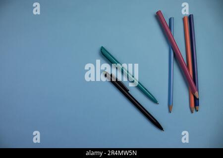 Colored pencils photographed from above, placed on the edge of a blue background. Stock Photo