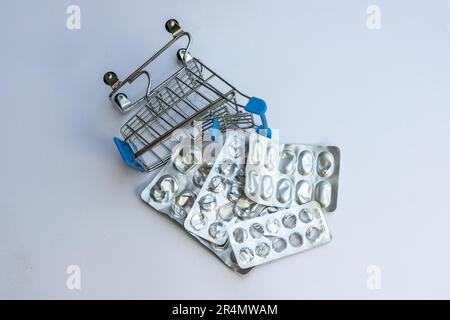 Consumed pills and tablet strips in a mini shopping trolley. Medicine consumption concept. Stock Photo