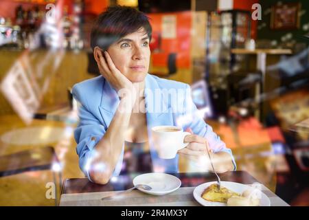 Wistful lady drinking coffee in cafeteria Stock Photo