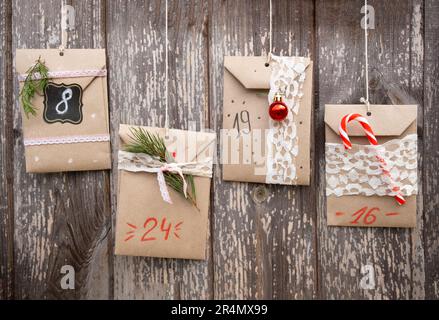 Christmas Advent Calendar. Sweets hidden in paper bags hanging on wooden background. Seasonal activity for kids, family winter holidays. Handmade tink Stock Photo