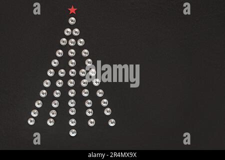 Christmas tree of screws on a black background. Flat lay. Copy space. Unusual Christmas tree made of construction tools. Creative Industrial greeting Stock Photo