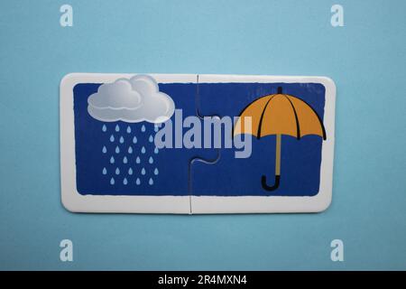 Picture puzzles superimposed on a blue background. Rain cloud and umbrella photographed from above. Stock Photo