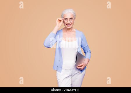 Grey haired old smiling business woman wearing glasses, holding tablet. Isolated over violet purple background Stock Photo