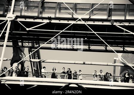 PARIS, FRANCE - AUGUST 6, 2017: Visitors of Pompidou Centre admiring cityscape in sunset light from the balcony. Black white historic photo Stock Photo