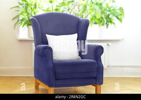 Throw pillow mockup: blank white pillowcase on retro blue wingback chair, for customized print on demand picture product services. Stock Photo