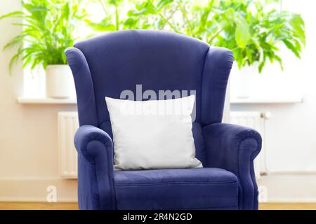 Throw pillow mockup: blank white pillowcase on retro blue wingback chair, for customized print on demand picture product services. Stock Photo
