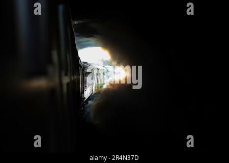 Creative image of the Flying Scotsman LNER Class A3 steam locomotive exiting a tunnel into the sunlight on the Keighley & Worth Valley Railway Stock Photo