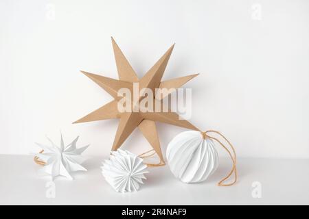 Christmas Paper Star and Ball Decoration. Handmade Christmas Nordic Decor on a Light Background against the Wall. Boho, Scandinavian Style Design. DIY Stock Photo