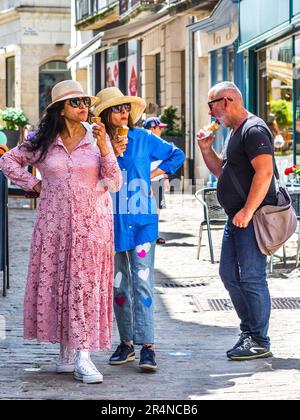 Three tourists eating ice cream cornets in city street - Loches, Indre-et-Loire (37), France. Stock Photo