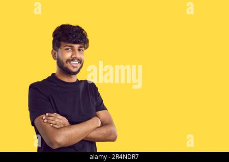 Young Indian man in pose of confident person, smiling crossing arms in front of him stands in studio Stock Photo