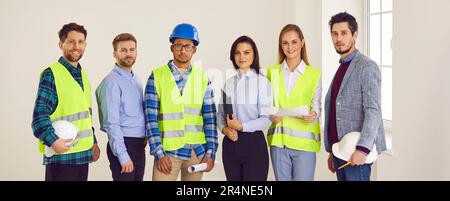 Group of engineers and architects standing on a building site and smiling. Stock Photo