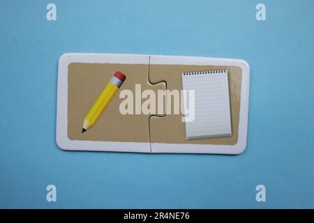 Picture puzzles placed on a blue background. Pen and notepad. Stock Photo