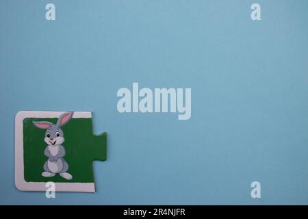 Information puzzles, photographed from above, placed on the edge of the blue background. Happy white rabbit. Stock Photo