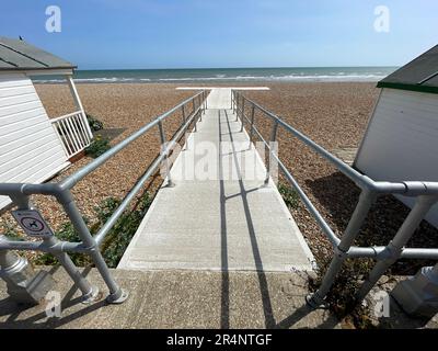 A walkway ramp suitable for wheelchair users has been built out onto a beach in between wooden beach huts. Stock Photo