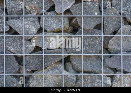 Stones behind the metal grating, stone wall background. Stock Photo