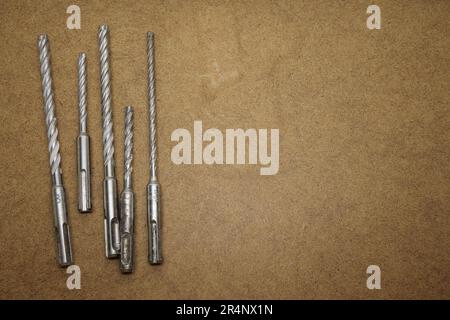 Selection of masonry drill bits on top of the brown MDF board Stock Photo